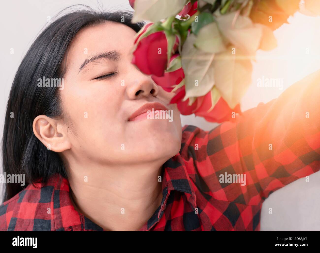The girl wearing a black-red striped dress sniffing red roses, red roses represent love on Valentine's Day, the idea of giving love to each other. Stock Photo