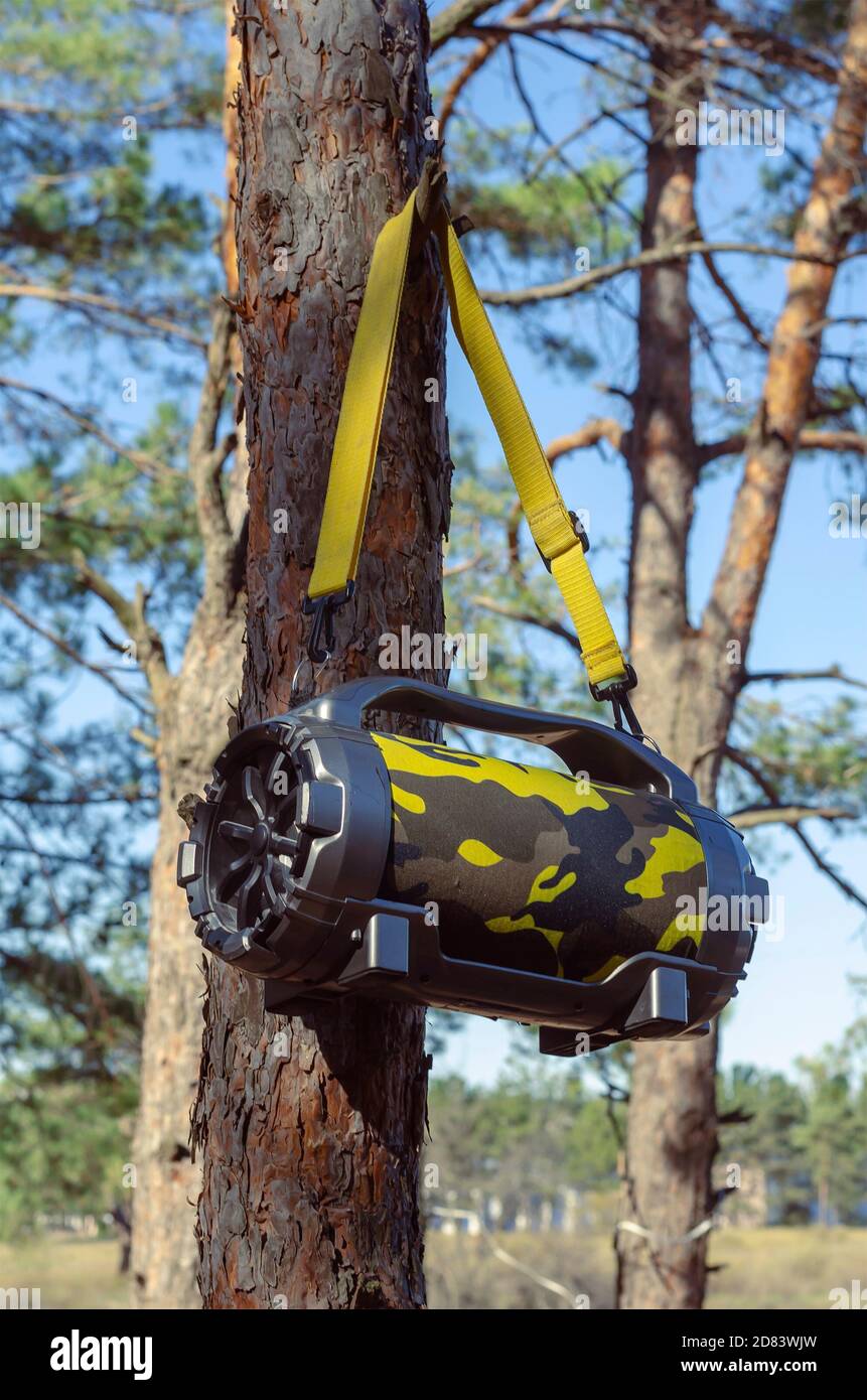 Outdoor Portable Wireless Bluetooth Speaker With Subwoofer Big hanging on  tree in the forest. Acoustic portable speaker camouflage color with yellow  c Stock Photo - Alamy