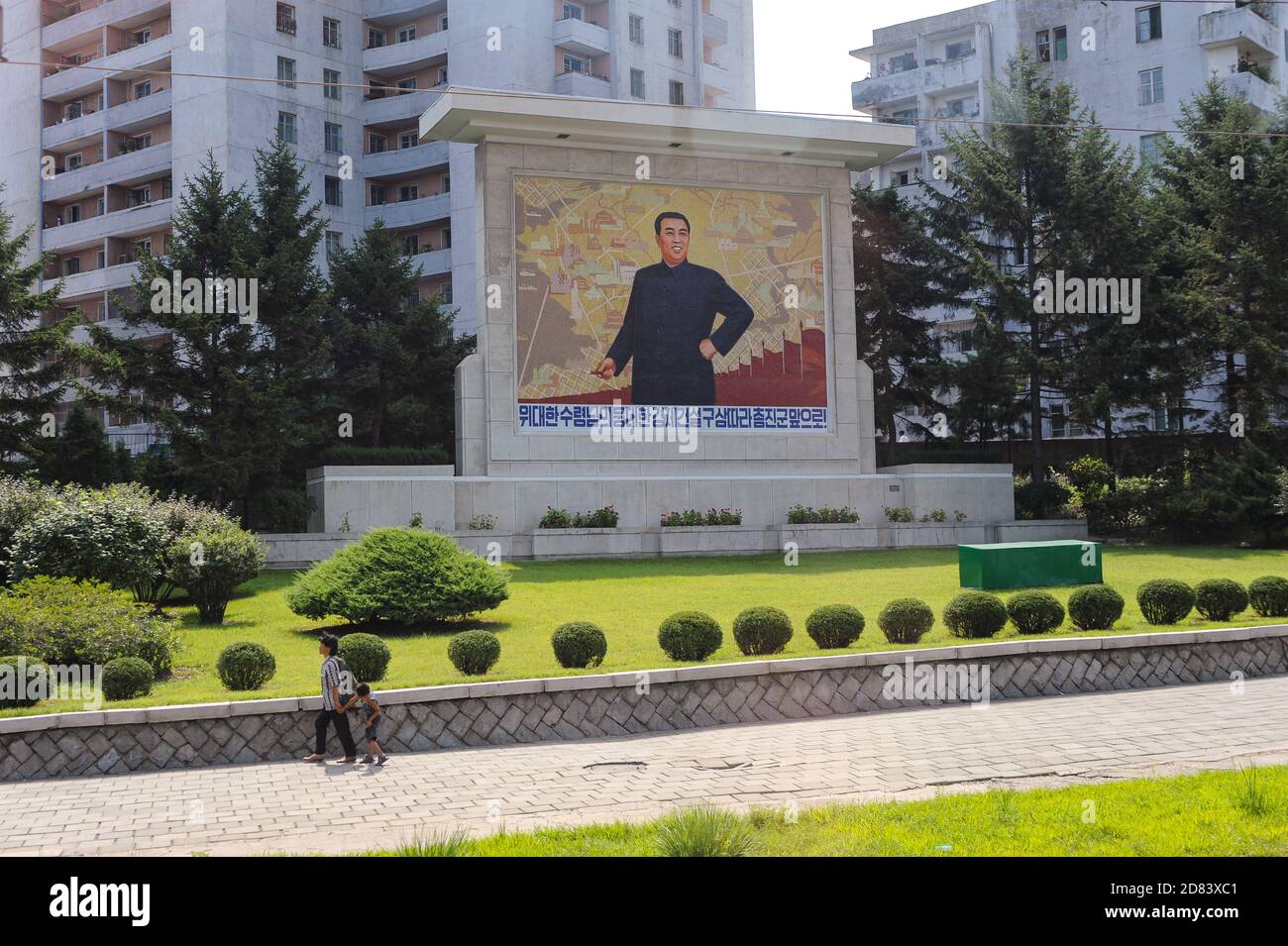 08.08.2012, Pyongyang, North Korea, Asia - An everyday street scene depicts a memorial with the portrait of Kim Il Sung and residential buildings. Stock Photo
