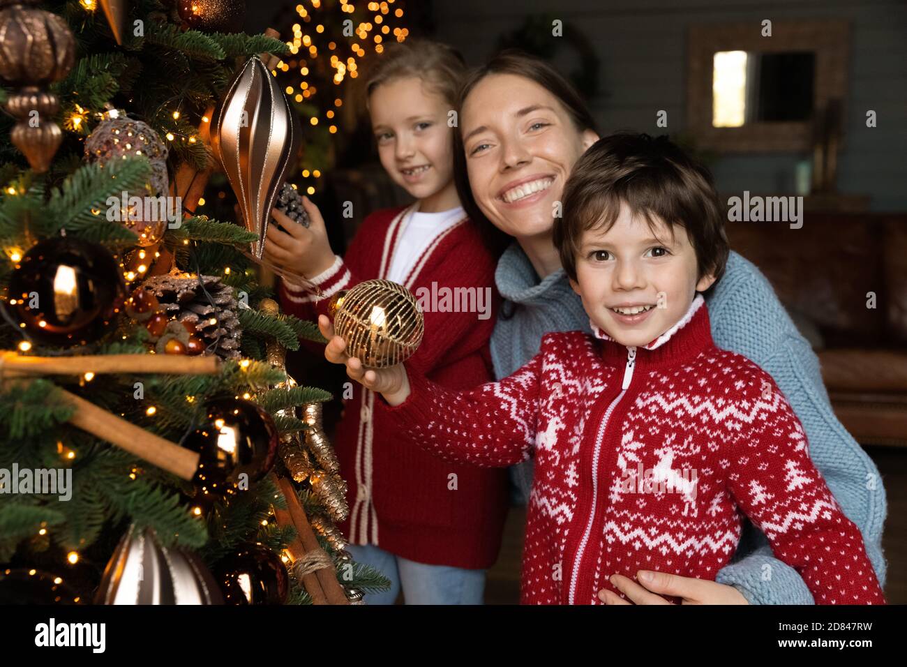 Portrait of happy mom and kids decorate Christmas tree Stock Photo