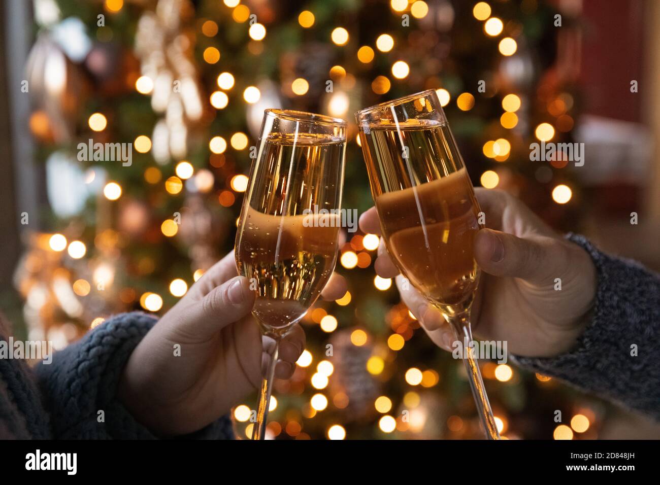 Close up of couple clink glasses celebrating New Year Stock Photo