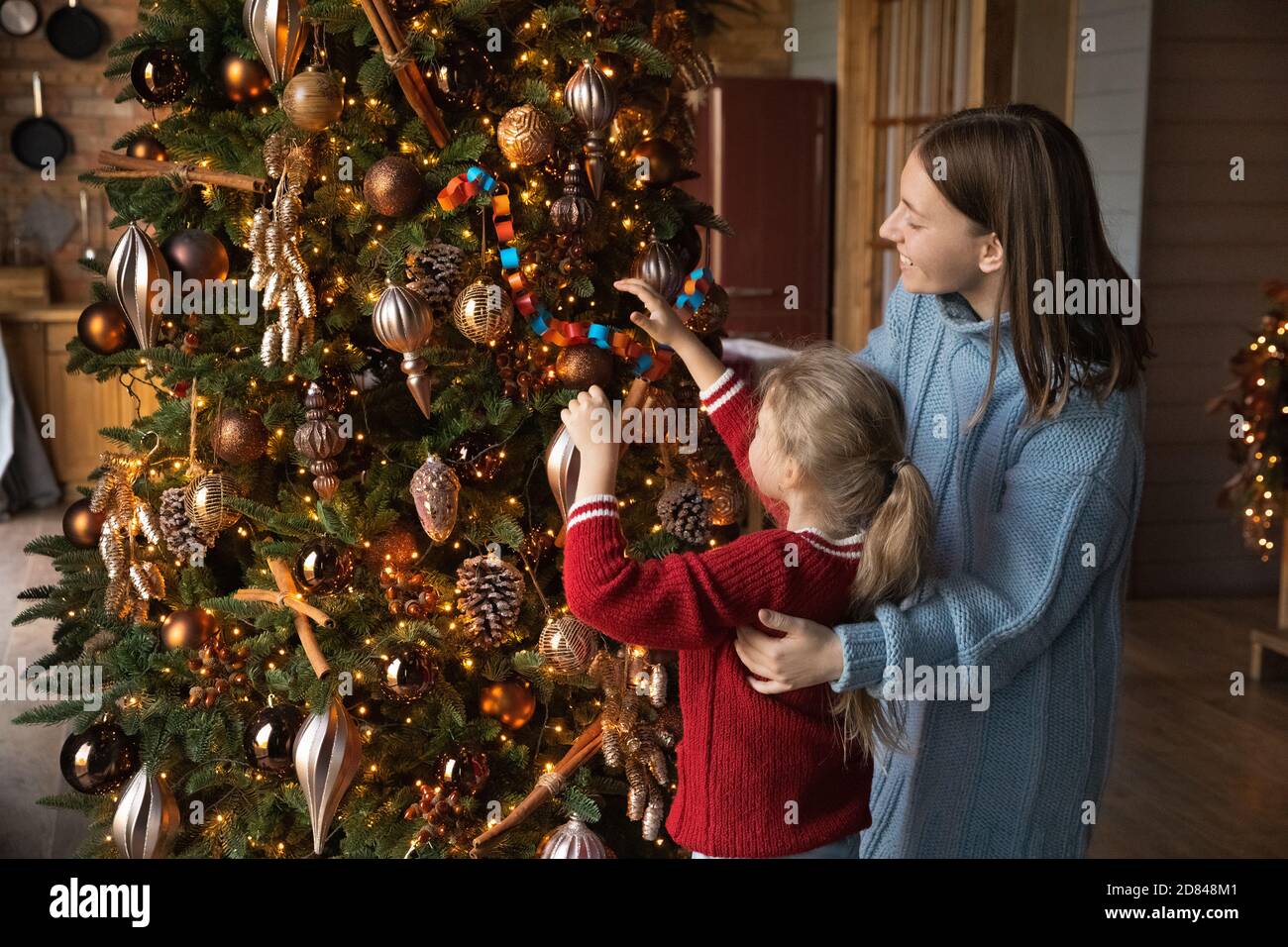 Mom and daughter decorate the Christmas tree Stock Photo by