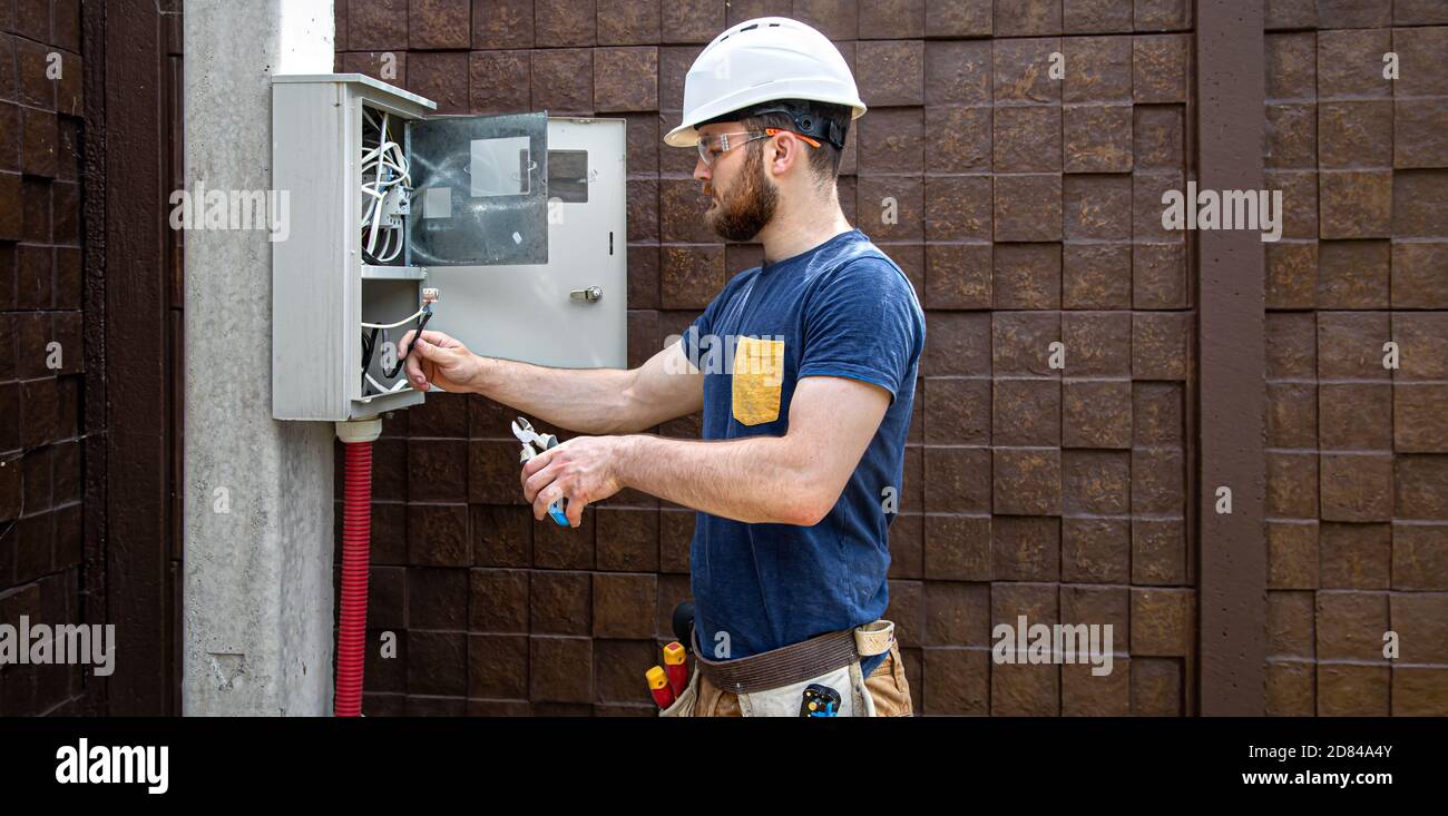 Electrician Builder at work, examines the cable connection in the electrical line in the