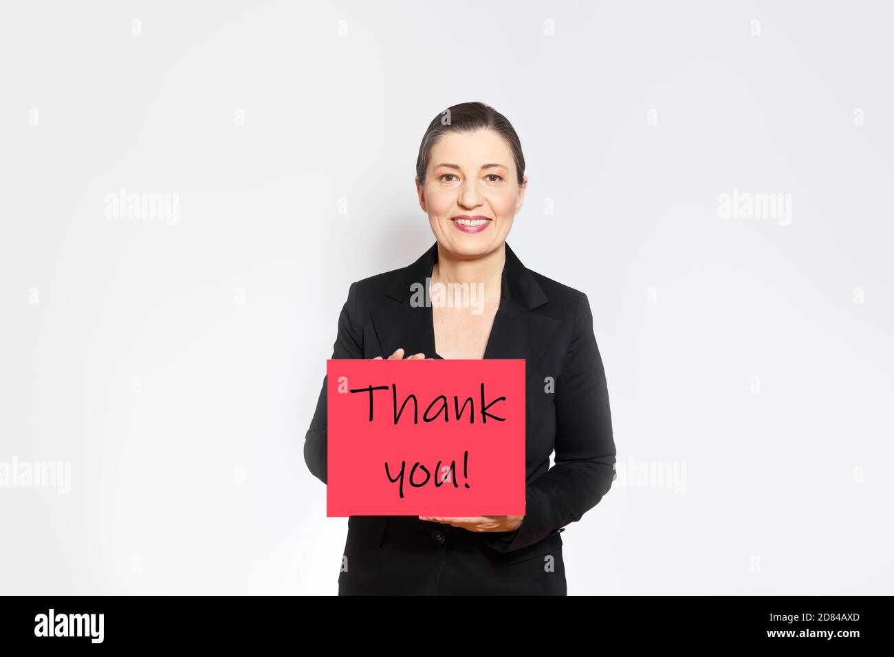 Smiling employer in black business outfit holding up a red card with text Thank you! Stock Photo