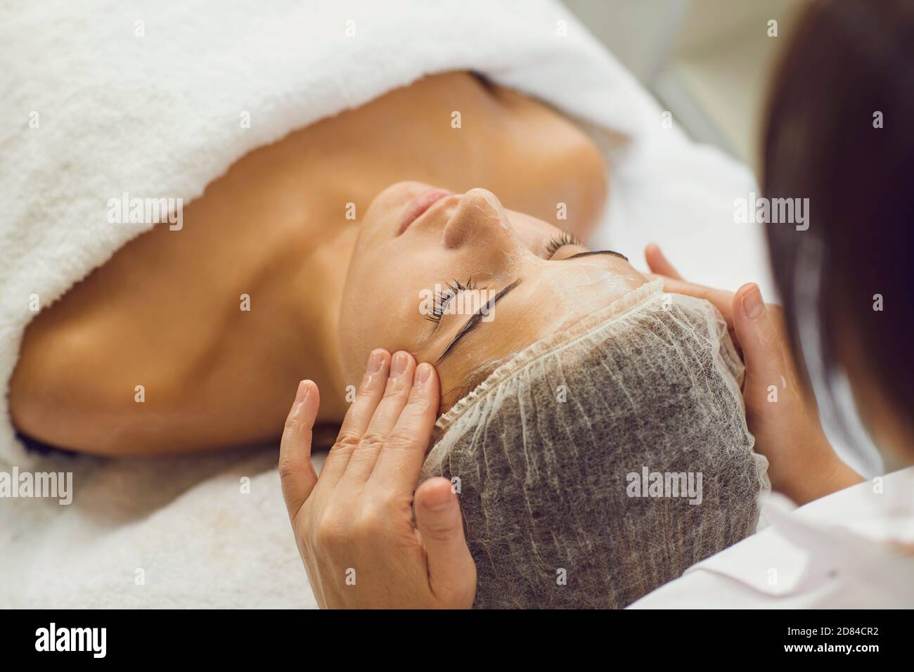 Face massage. Close-up of young woman getting spa massage treatment at beauty spa salon. Stock Photo