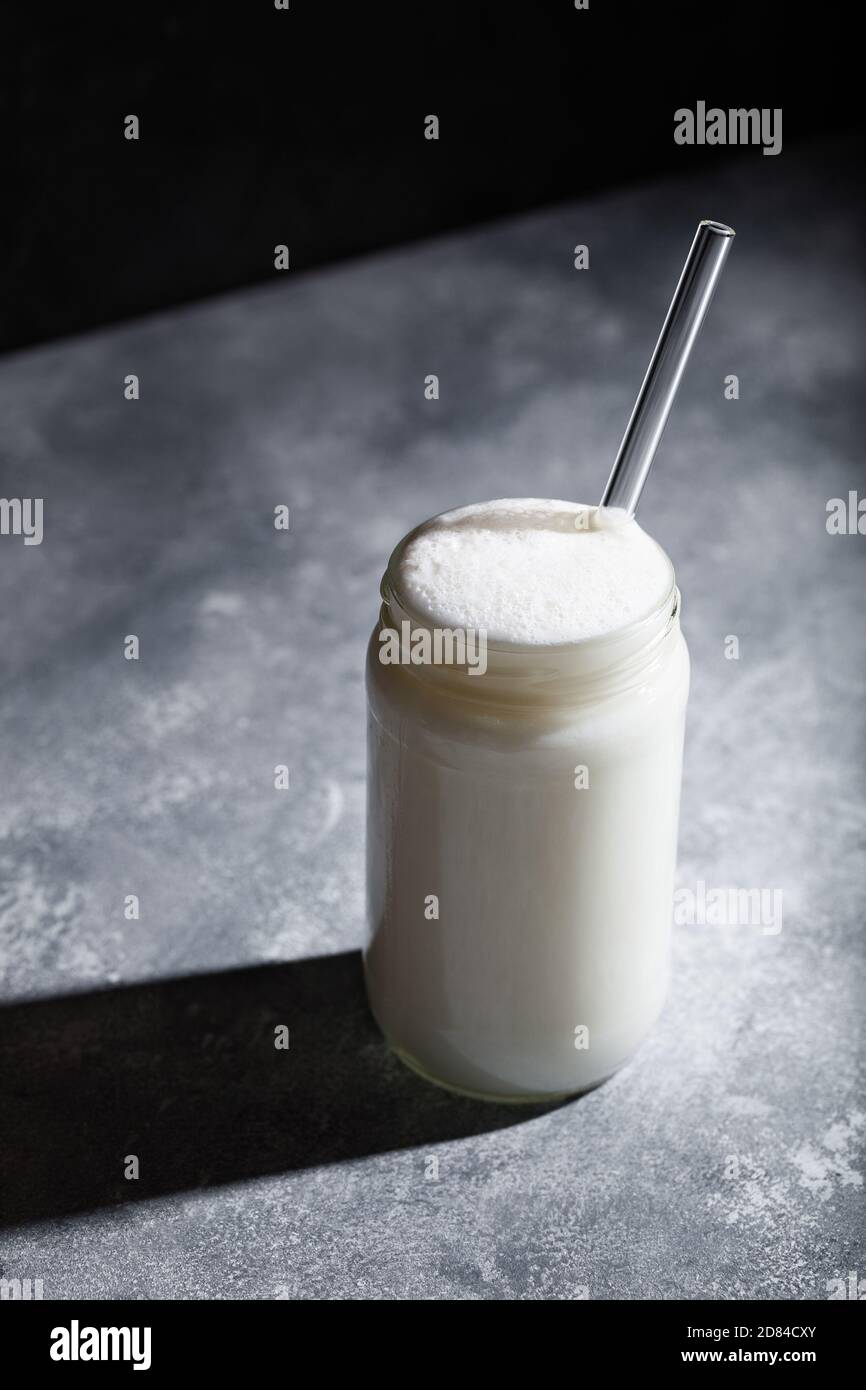 Ayran Turkish sparkling yogurt drink in glass jar with straw on gray background. Healthy probiotic beverage Stock Photo