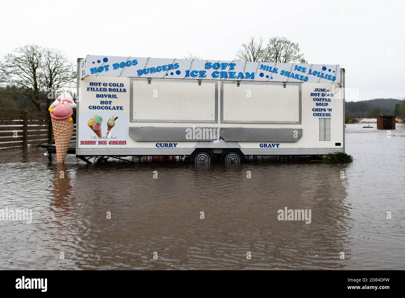Catering trailer with ice cream sign standing in flooded car park - Aberfoyle, Stirlingshire, Scotland, UK - 10 December 2019 Stock Photo
