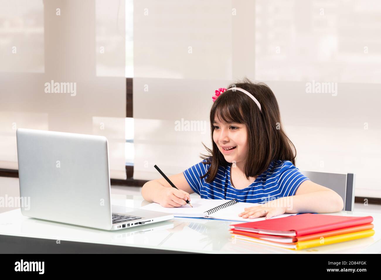 A little girl of 6 years old from first grade old homeschooling through video conference. Stock Photo