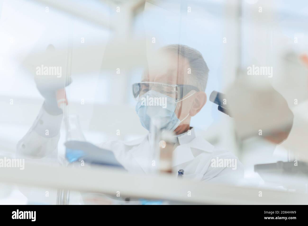 scientist sitting using an automatic dispenser for his research. Stock Photo