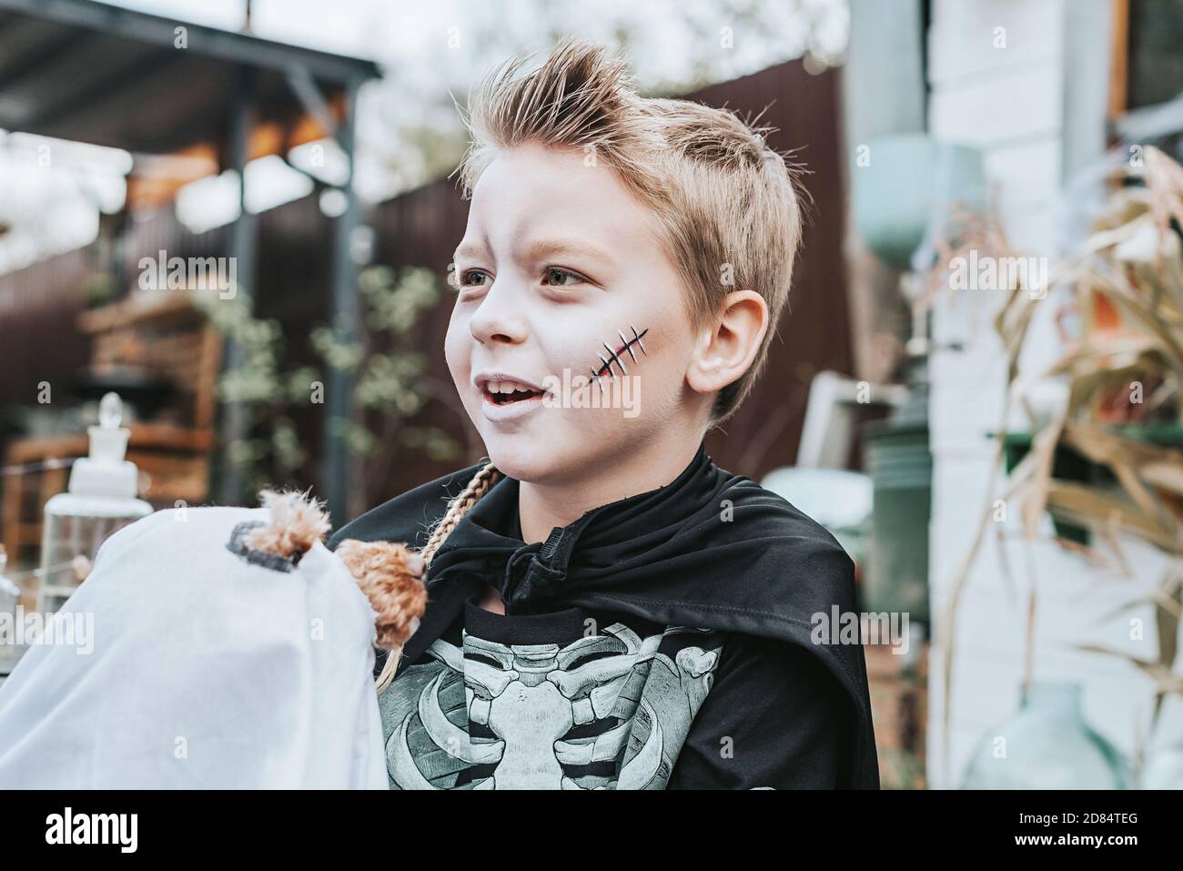 a boy in a skeleton costume with a dog in a ghost costume on the porch