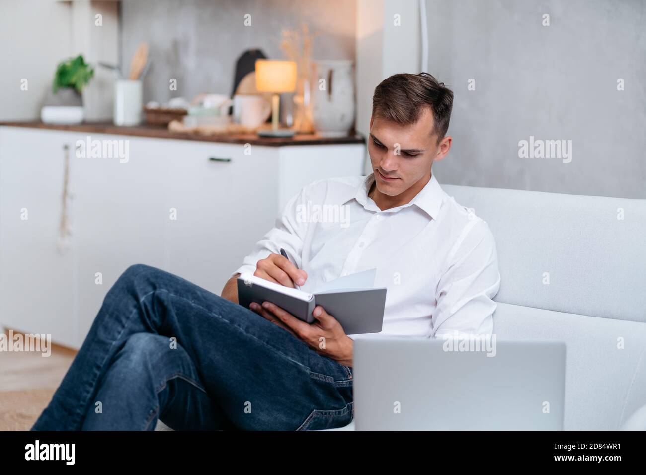 young man taking notes sitting on the couch . Stock Photo