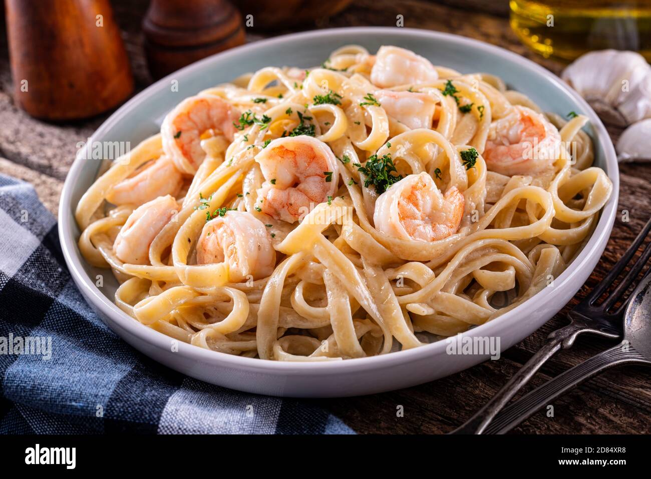 A plate of delicious shrimp alfredo with garlic and cream sauce over pasta. Stock Photo