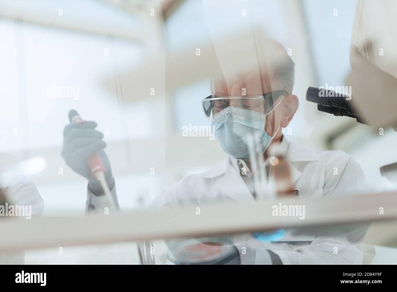 scientist sitting using an automatic dispenser for his research. Stock Photo