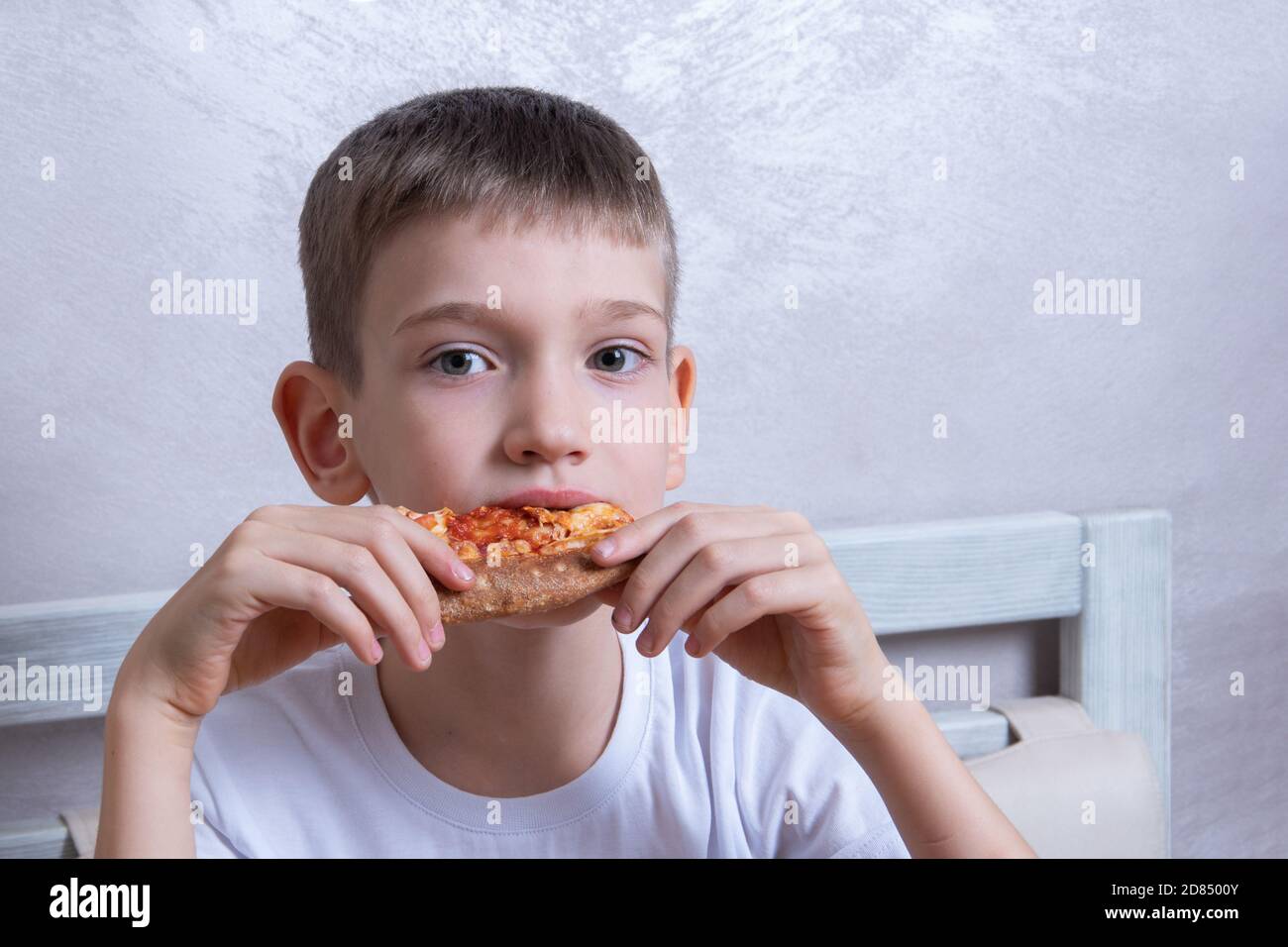 Cute boy eating a slice of pepperoni and cheese pizza, closeup, copy