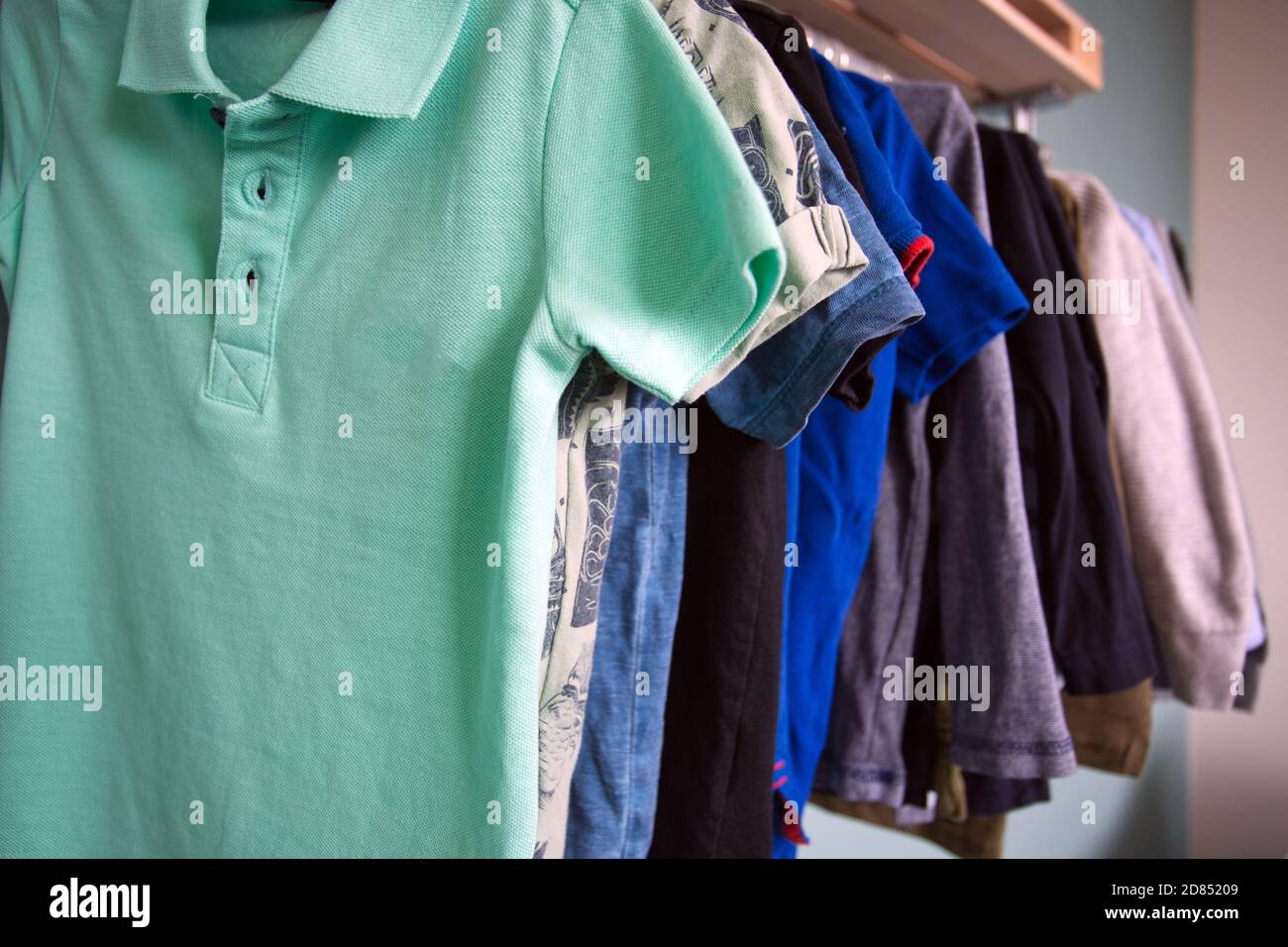 Boys dressing clothes hanging in metal rack, childrens room of boys storage in room Stock Photo