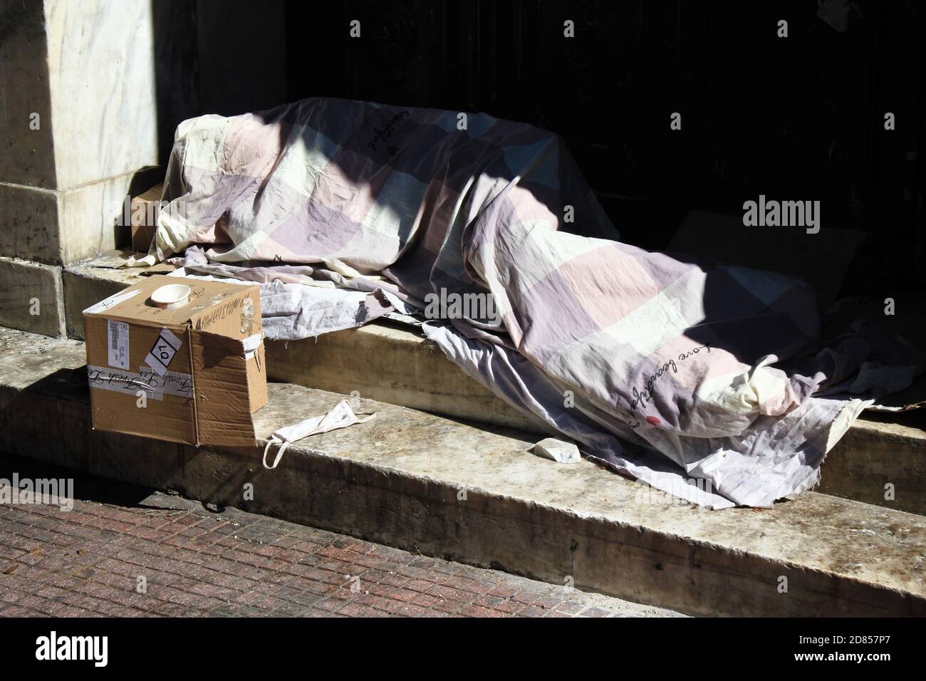 An unidentified homeless person sleeping in front of the entrance of ...