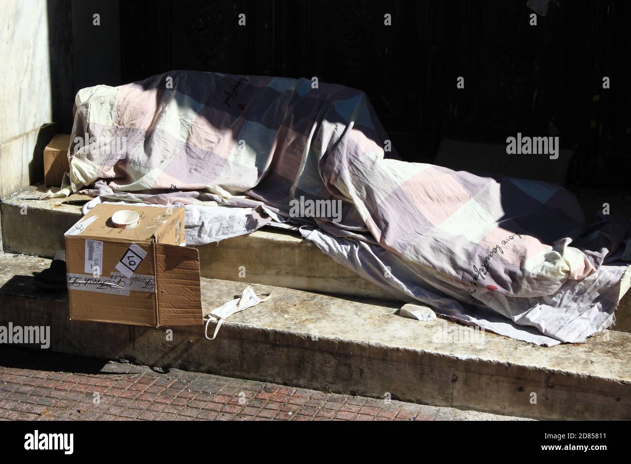 An unidentified homeless person sleeping in front of the entrance of ...