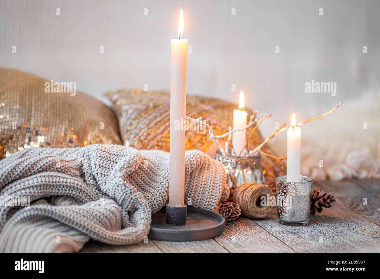 Cozy home interior, burning candles, warm sweater on a wooden  table.Seasonal autumn-winter concept of a cozy home, minimal decoration,  warming Stock Photo - Alamy