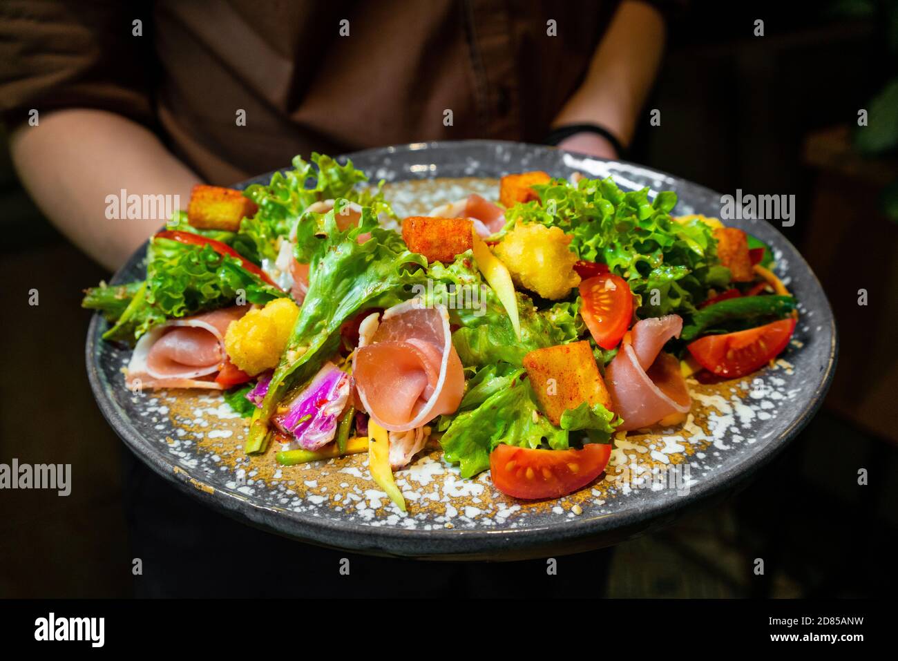 Female hands holding hydroponic vegetable bacon salad with wooden table background. Stock Photo