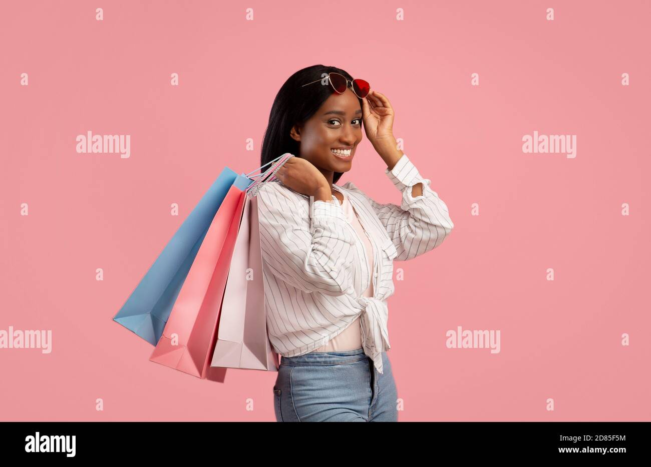 Gorgeous young woman with shopping bags smiling and looking at camera ...