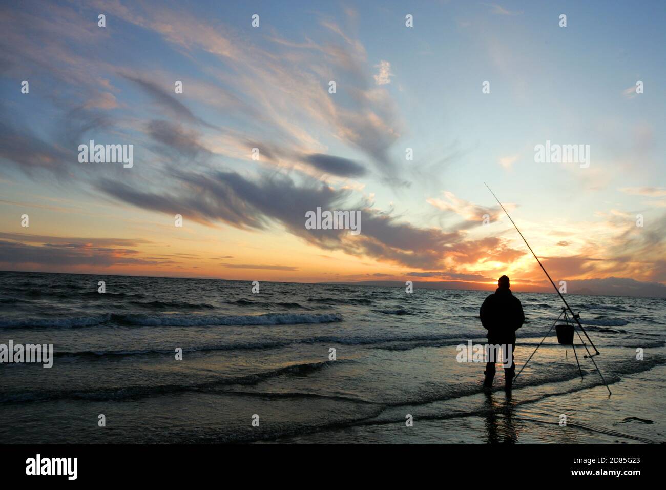 Croy Shore, Croy Bay, Carrick, Ayrshire, Scotland, UK.As the sunset over the Firth of Clyde on the West Coast of Scotland a fisherman sets his rod and line up for an evening of sea fishing. July 2012 Stock Photo