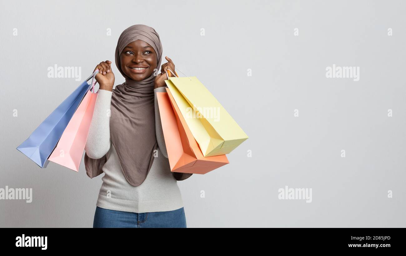 Happy black muslim shopaholic woman in hijab posing with lots shopper bags Stock Photo