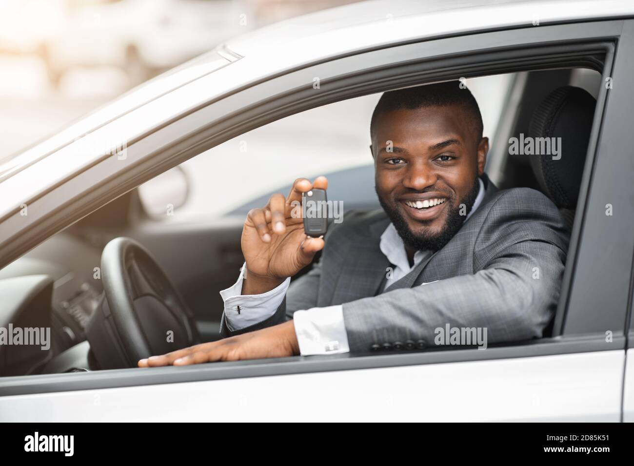 Happy black guy in suit holding key from new car Stock Photo - Alamy