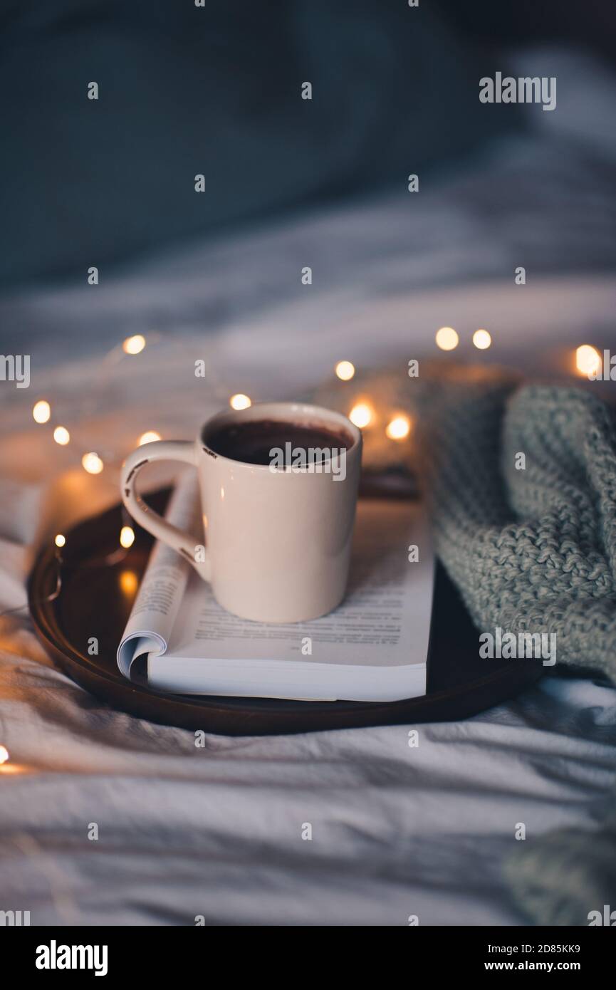 Cup of fresh coffee on open folded book staying on wooden tray in ...