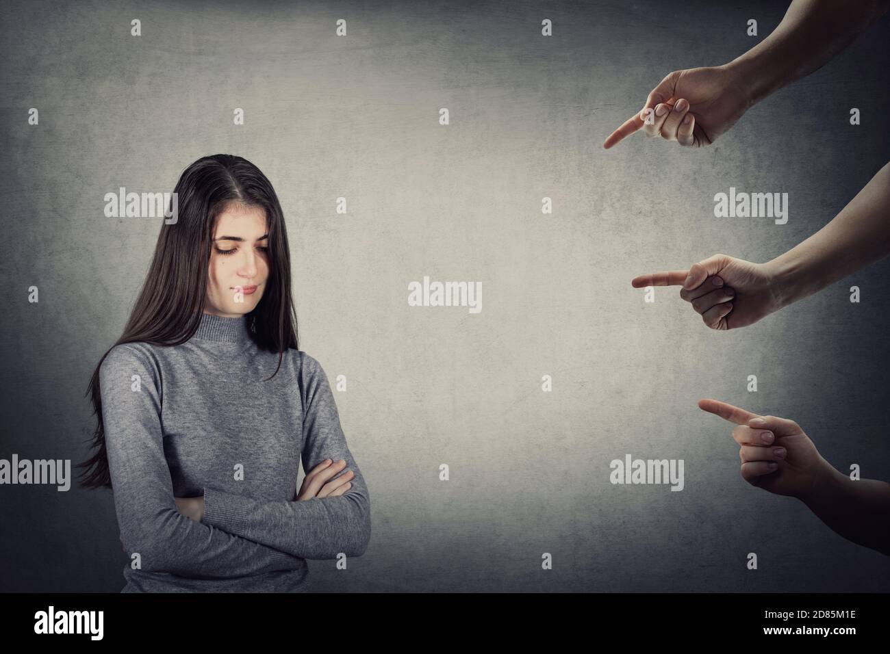 Stressed teenage girl, under pressure, looking down feel ashamed and discomfort as multiple hands pointing forefingers, blaming as guilty. Upset stude Stock Photo