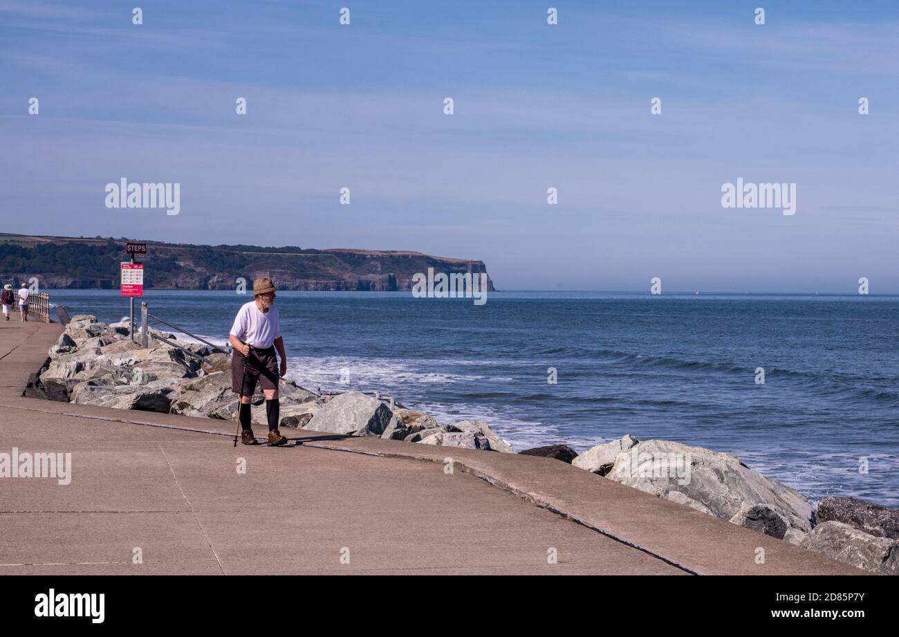 Senior man walking along sea front, Whitby, England, UK Stock Photo