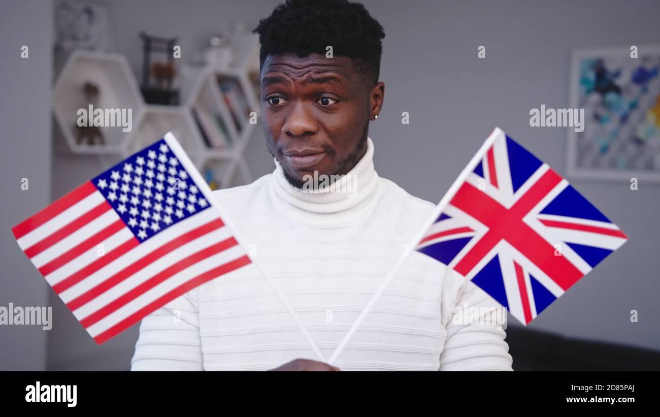 Confused black man holding USA and UK flags. Immigration choice. High ...
