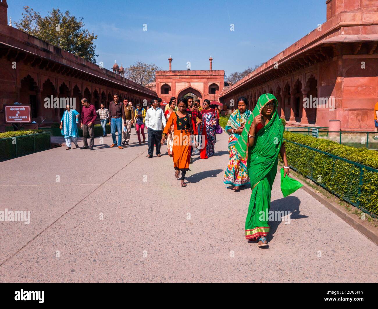 Agra, Uttar Pradesh, India - March 2019: A group of Indian tourists in colorful attire walking inside the red sandstone entrance to the Taj Mahal. Stock Photo