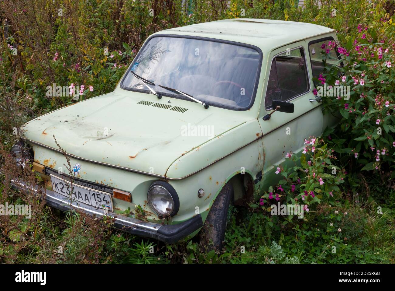 Novosibirsk, Russia - 09.19.2020: An old abandoned car with peeled paint and disassembled parts of the ZAZ brand of the Soviet past, overgrown with gr Stock Photo