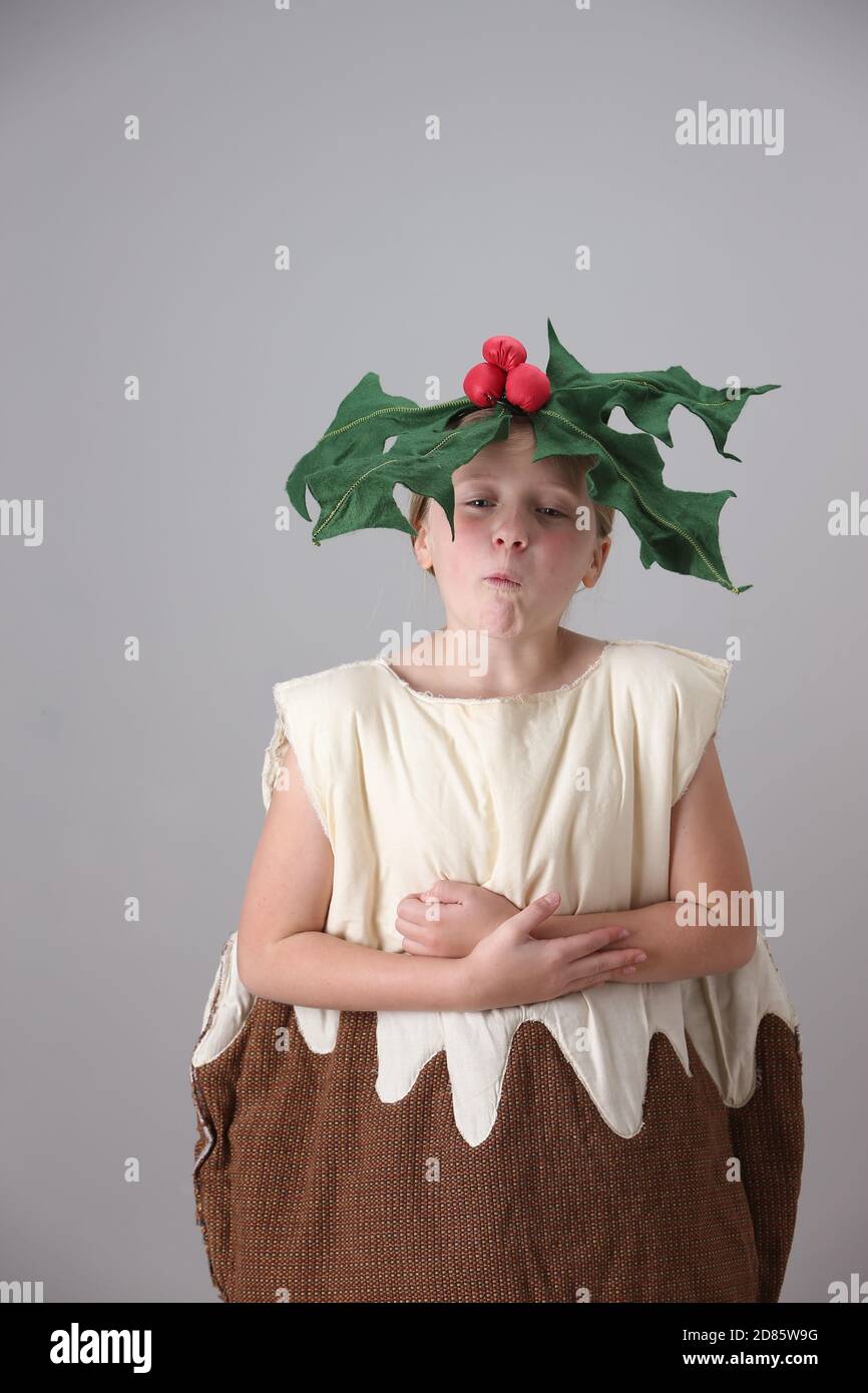 Young girl dressed as a Christmas pudding with holly on her head