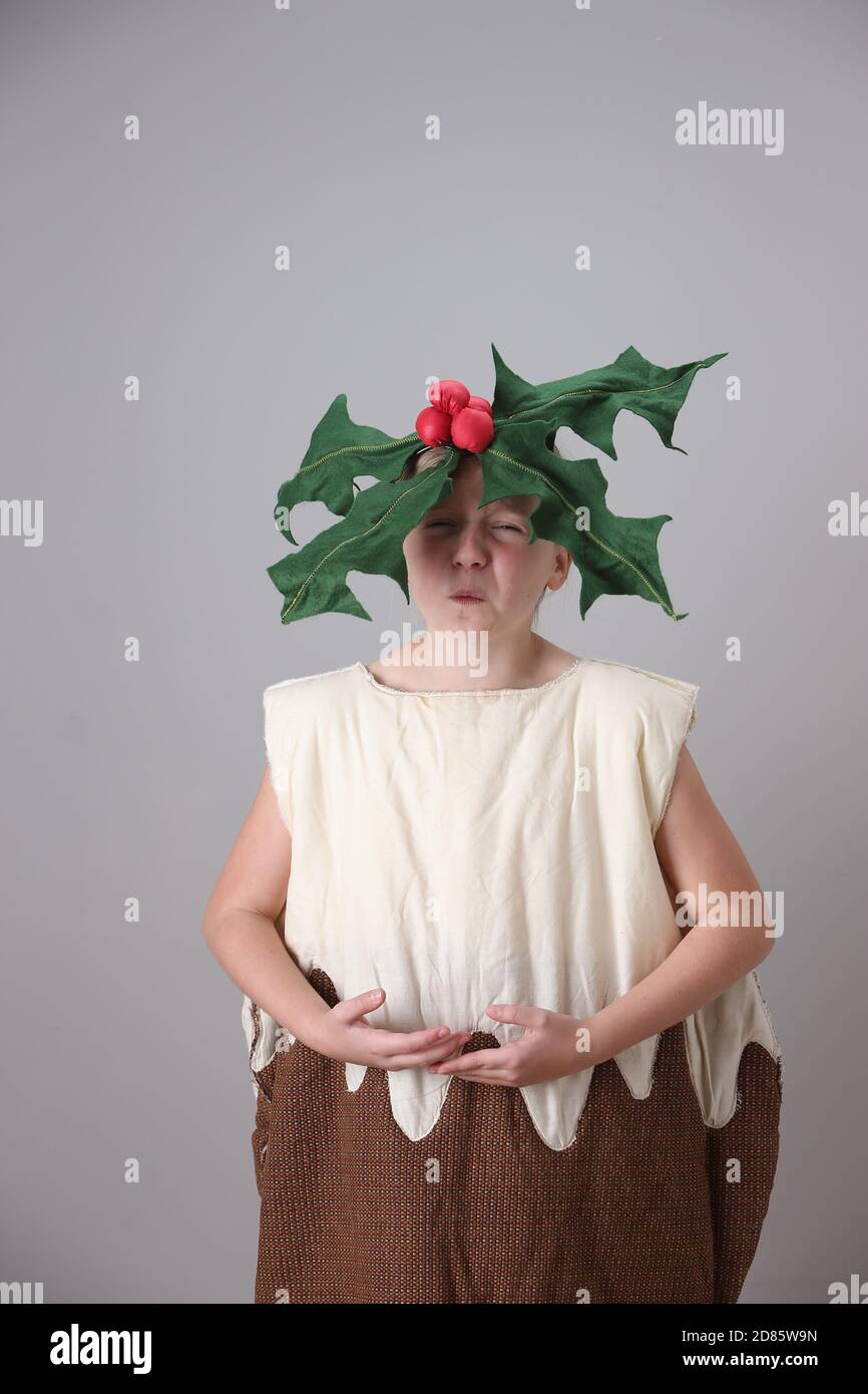 Young girl dressed as a Christmas pudding with holly on her head