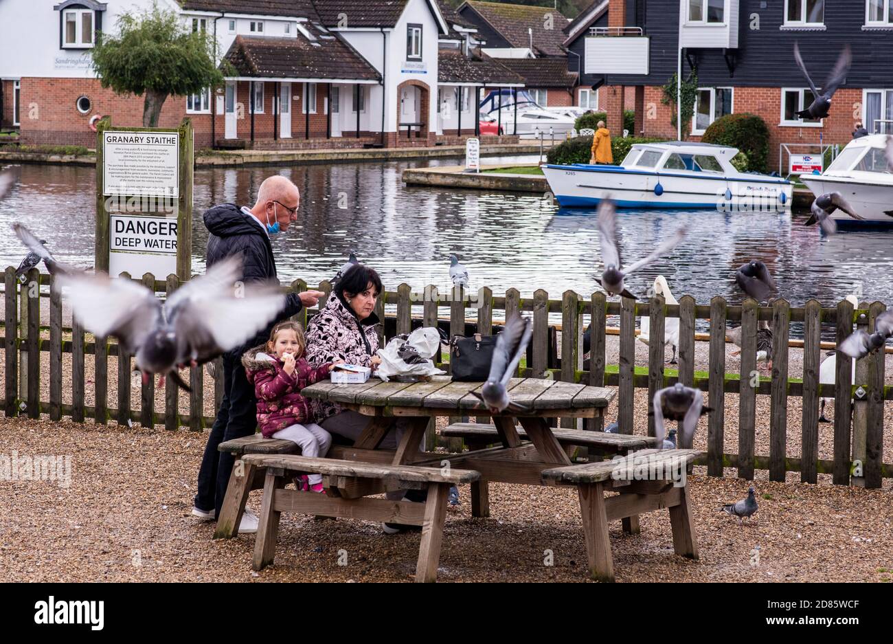 Family eating fish and chips on picnic bench, Wroxham, Norfolk, England, UK Stock Photo