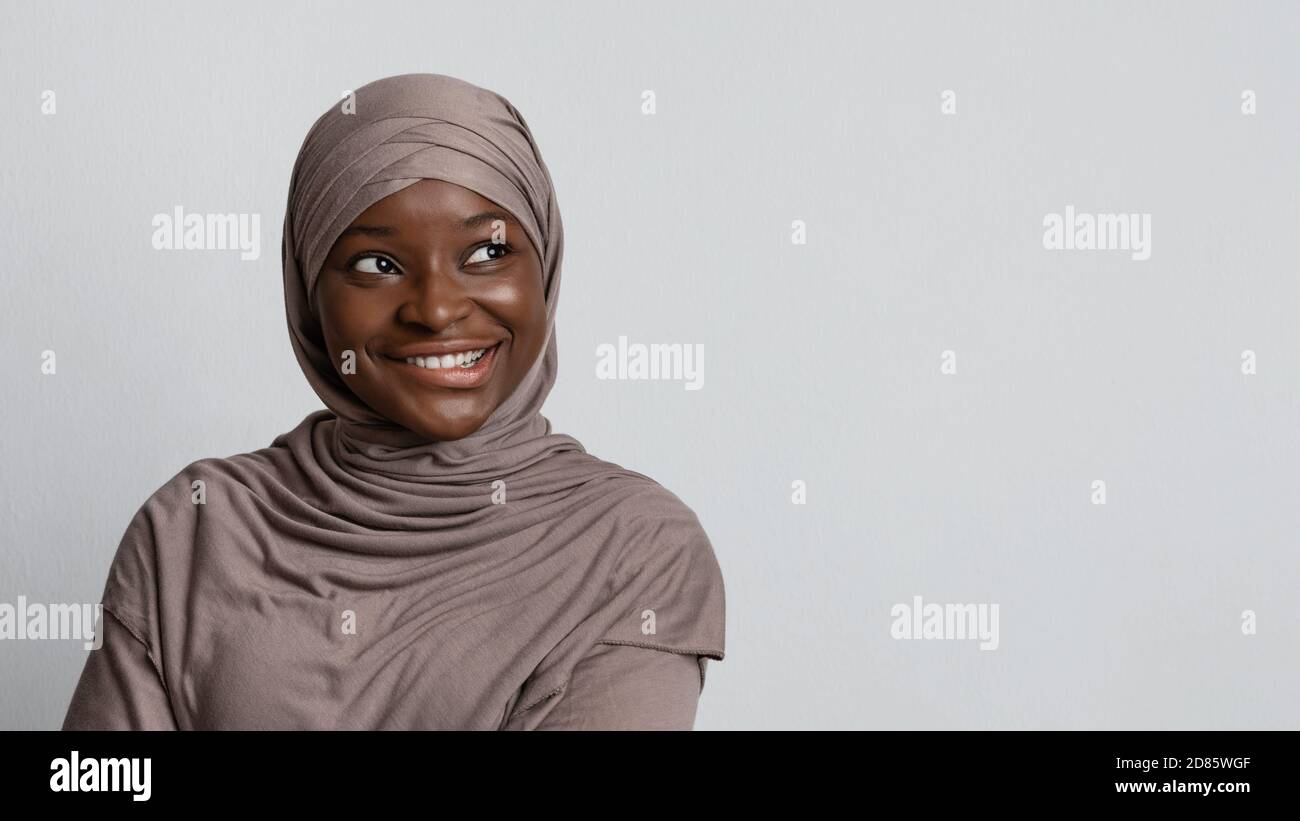 Curious black muslim woman looking at copy space, biting lip with excitement Stock Photo