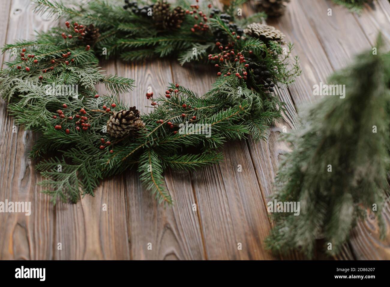 Modern christmas wreath with red berries, green branches, pine cones ...