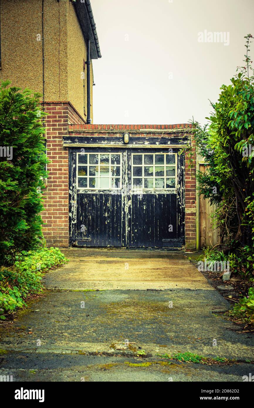 Worn and peeling paint on old black garage doors of a 1930's house in