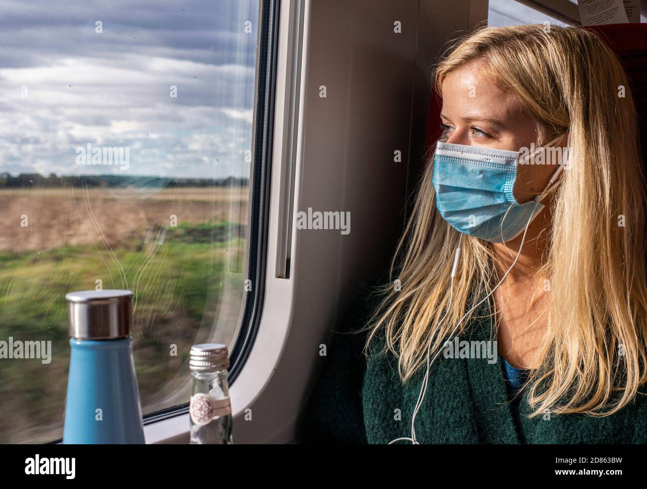 Woman wearing face mask on train looking through window Stock Photo