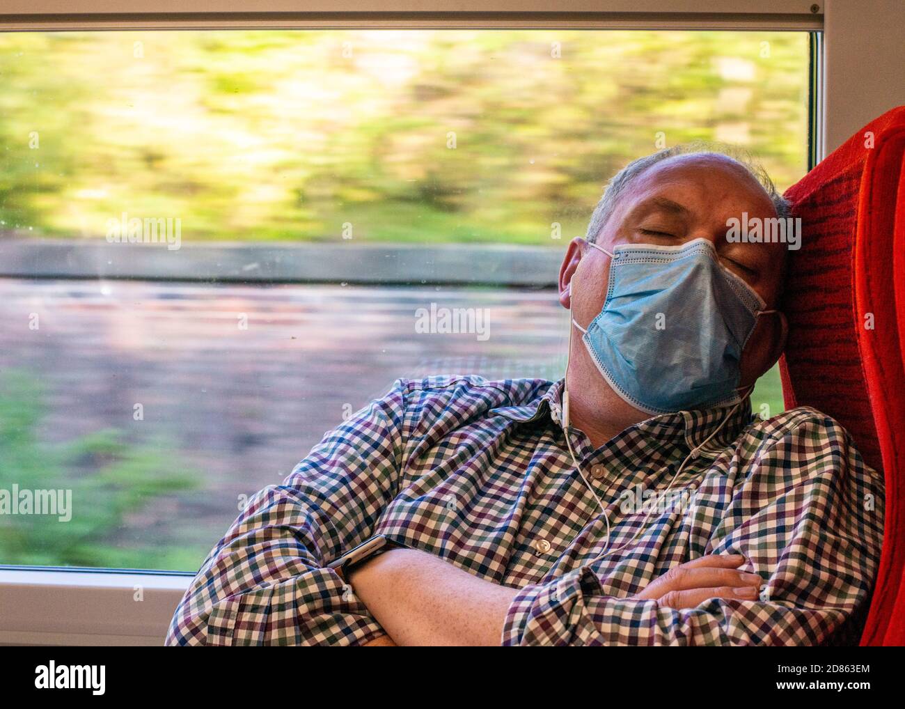 Man wearing face mask sleeping on train Stock Photo
