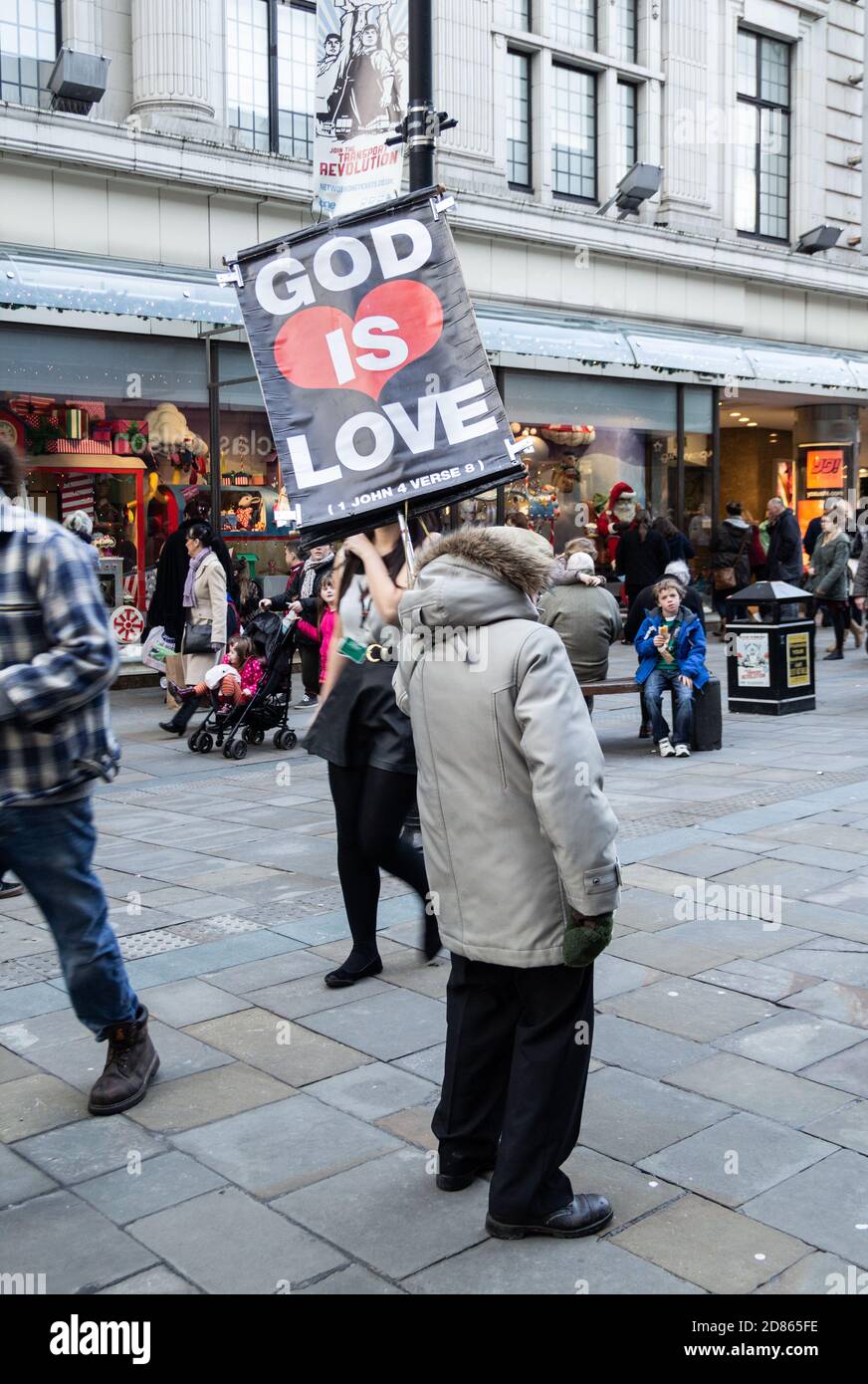 Elderly man holding God Is Love placard in Northumberland street in Newcastle upon Tyne, England, UK Stock Photo