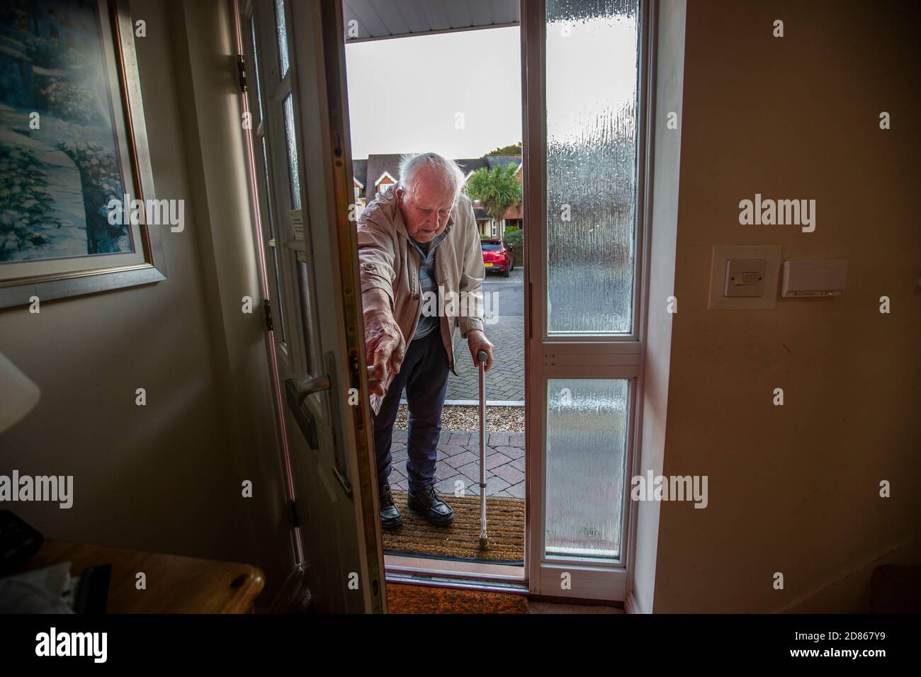 Elderly man in his 80's entering his home using a walking aid, Dorset, Southwest England, United Kingdom Stock Photo