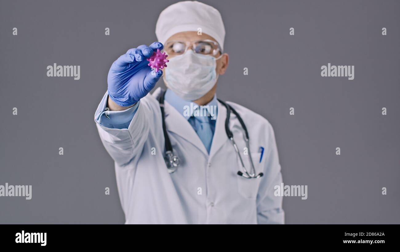Male lab assistant shows covid-19 virus cell, stop sign in research ...