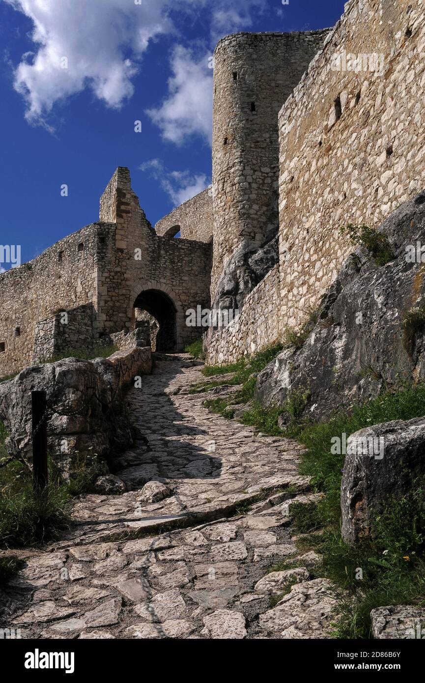 A paved path leads to the gateway of 13th century Spiš Castle (Spišský hrad), founded by the Hungarian kings on a limestone spur high above the surrounding countryside, now in the Košice Region of Slovakia.  It successfully repelled a Tartar siege in 1241 and grew to become Central Europe’s largest fortress complex.  Spiš was abandoned after a catastrophic fire in 1780, but a thorough restoration programme, launched in 1969, led to both the castle and its environs achieving UNESCO World Heritage Site status in 1993. Stock Photo