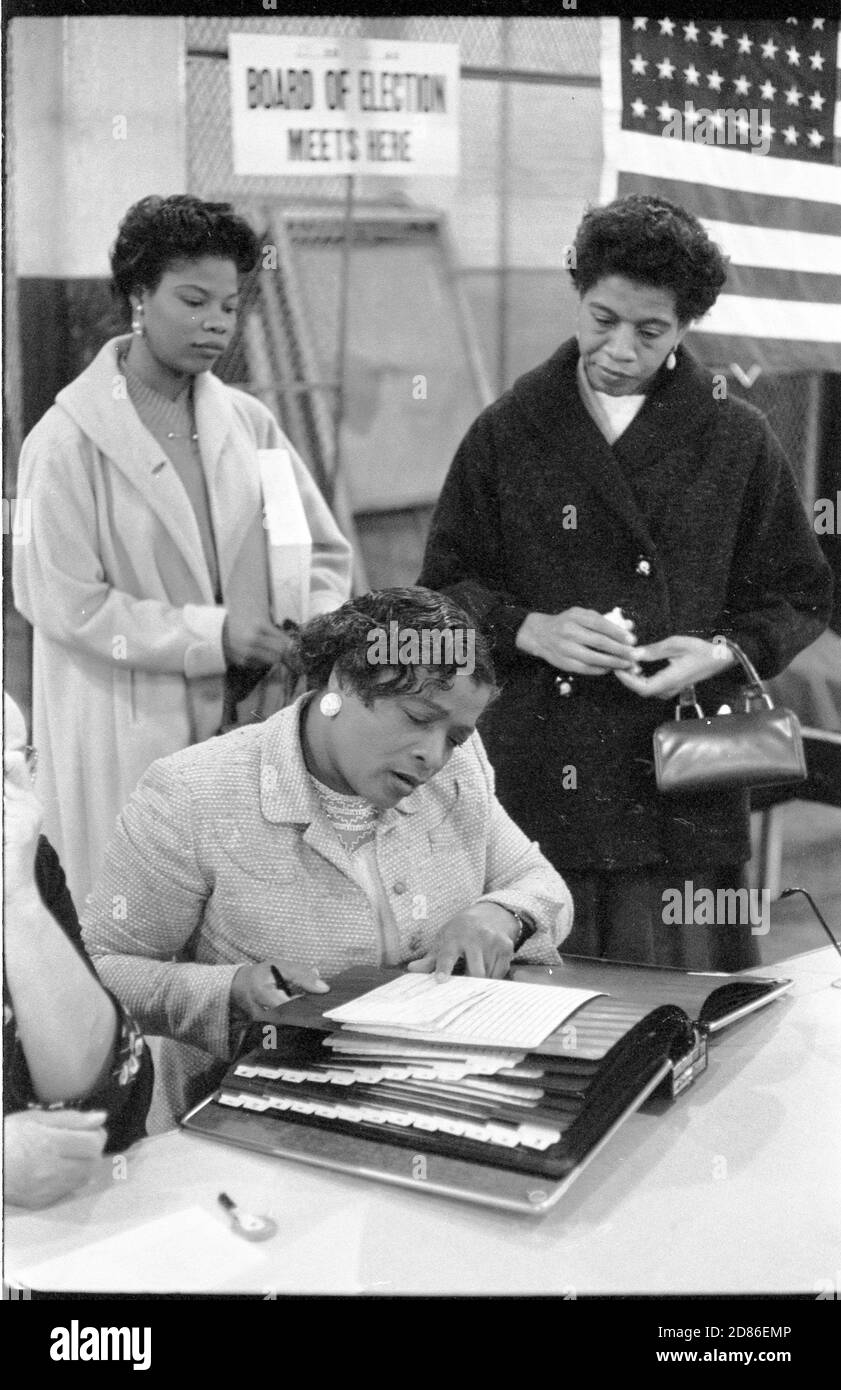 Three African-American women at a polling place, one looking at a book of registered voters, New York, NY, 11/5/1957. (Photo by Thomas J O'Halloran/U S News and World Report Collection/RBM Vintage Images) Stock Photo
