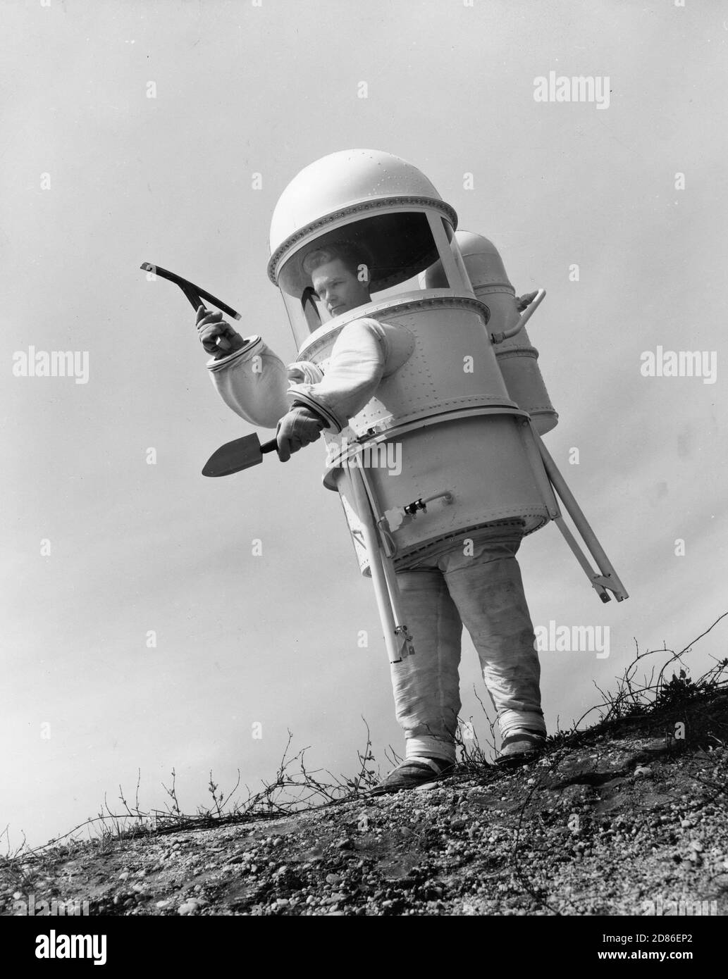 Two-piece lunar exploration suit, being developed to provide protection for future astronauts as they move about on the surface of the moon, is modeled by a scientist from the Republic Aviation Corporation's Life Sciences Laboratory. The suit includes tripod and built-in seat. Advanced models will carry instruments to provide complete indoor environment, from climate control to food supply, Farmingdale, NY, 1960. (Photo by Republic Aviation Corporation/RBM Vintage Images) Stock Photo