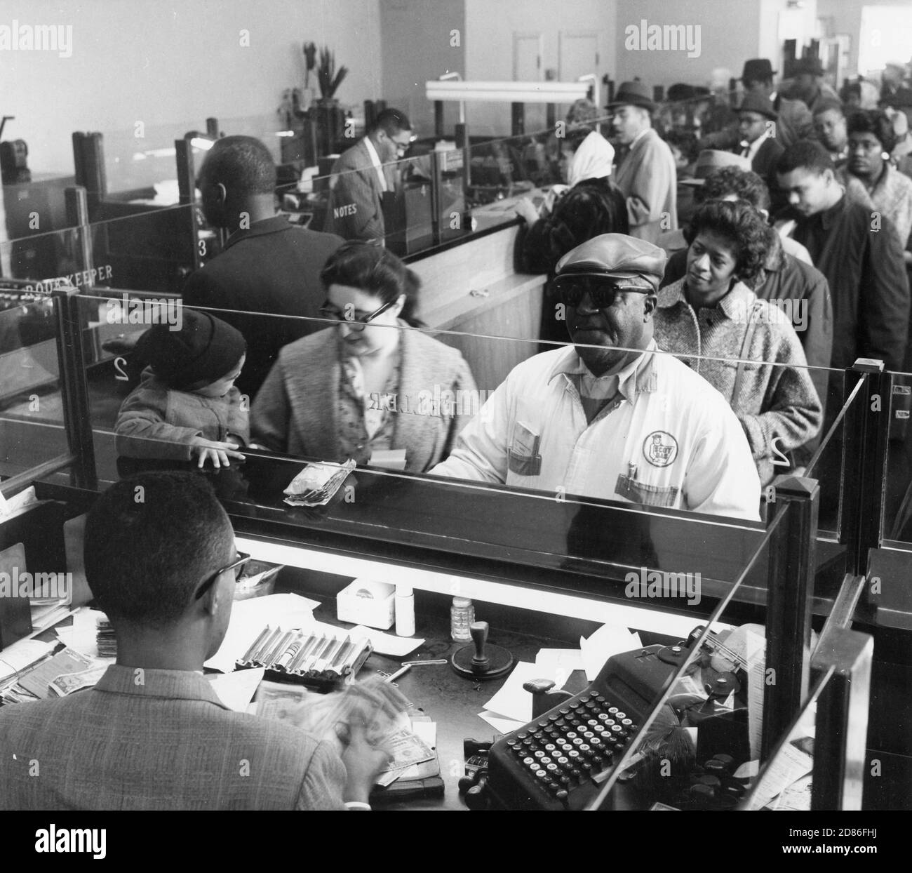 Customers crowd the teller lines to transact their banking business in the Industrial Bank, an historic African-American-owned bank based in Washington, DC whose board of directors, personnel and stockholders are African-Americans, Washington, DC, 1961. (Photo by Pinto/United States Information Agency/RBM Vintage Images) Stock Photo