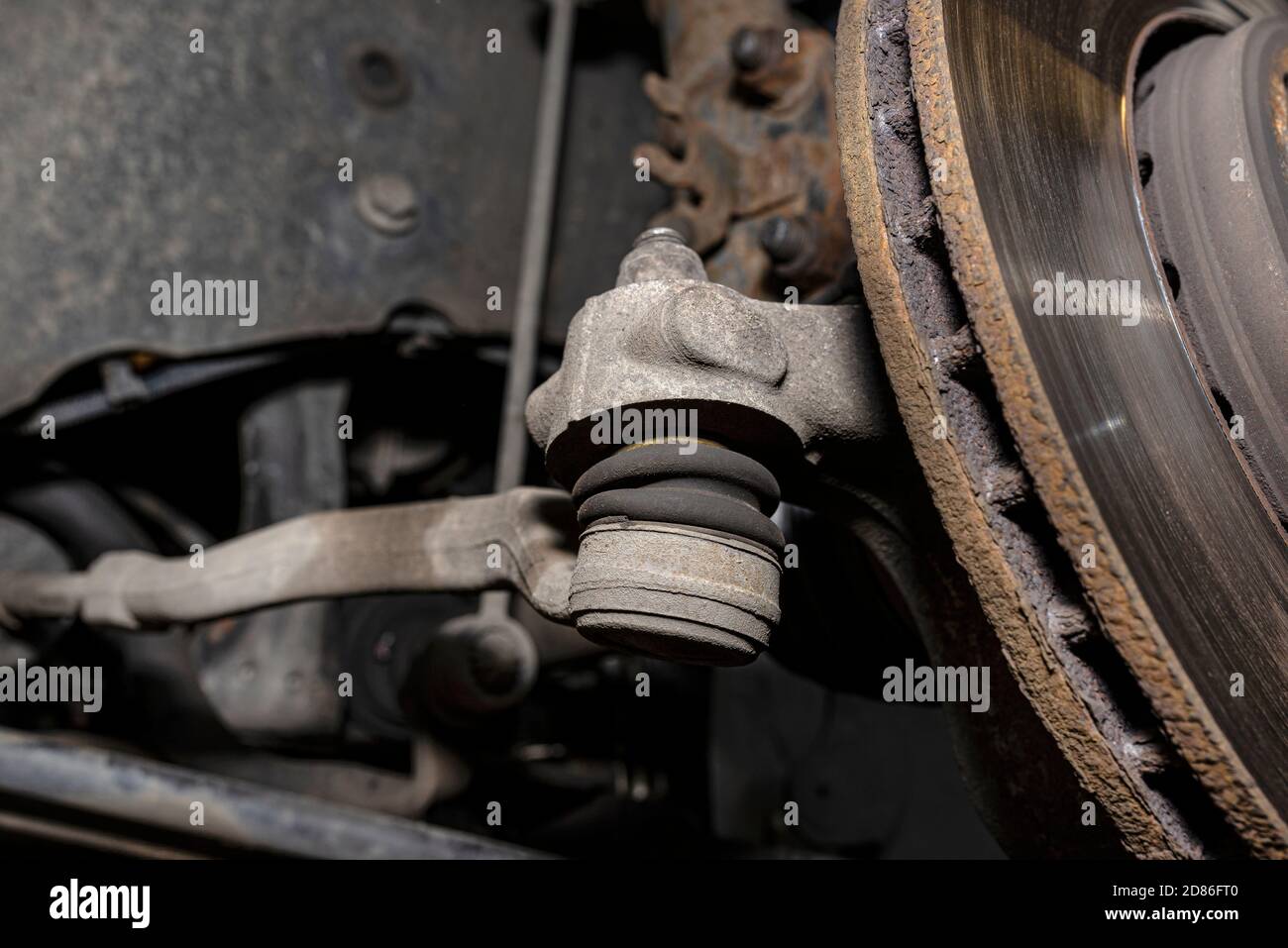 The end of the tie rod ends with a rubber connector, the brake disc is visible. Stock Photo