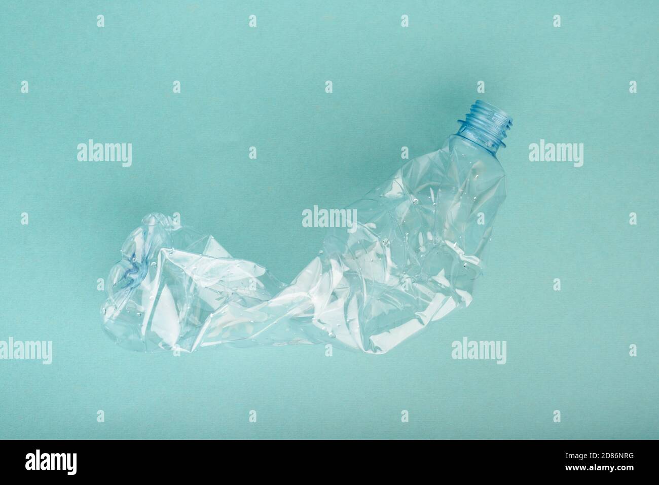 Used crushed plastic bottle on blue background. Stock Photo